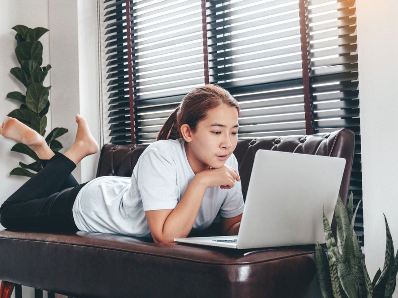 Person Laying On A Couch Using A Laptop