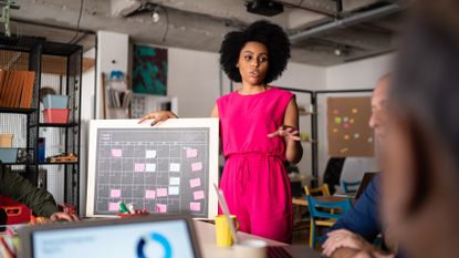 A young woman presents her ideas to colleagues in a conference room. 