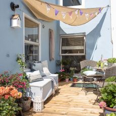 A small courtyard with wood decking, seating and an overhead canopy