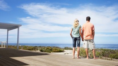 A couple standing on beach house porch holding hands