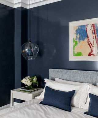 A bedroom color idea with navy blue walls, white ceiling and pendant light with oversized bulb