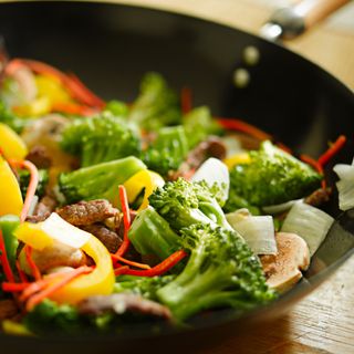 A wok holds a stir-fry with vegetables