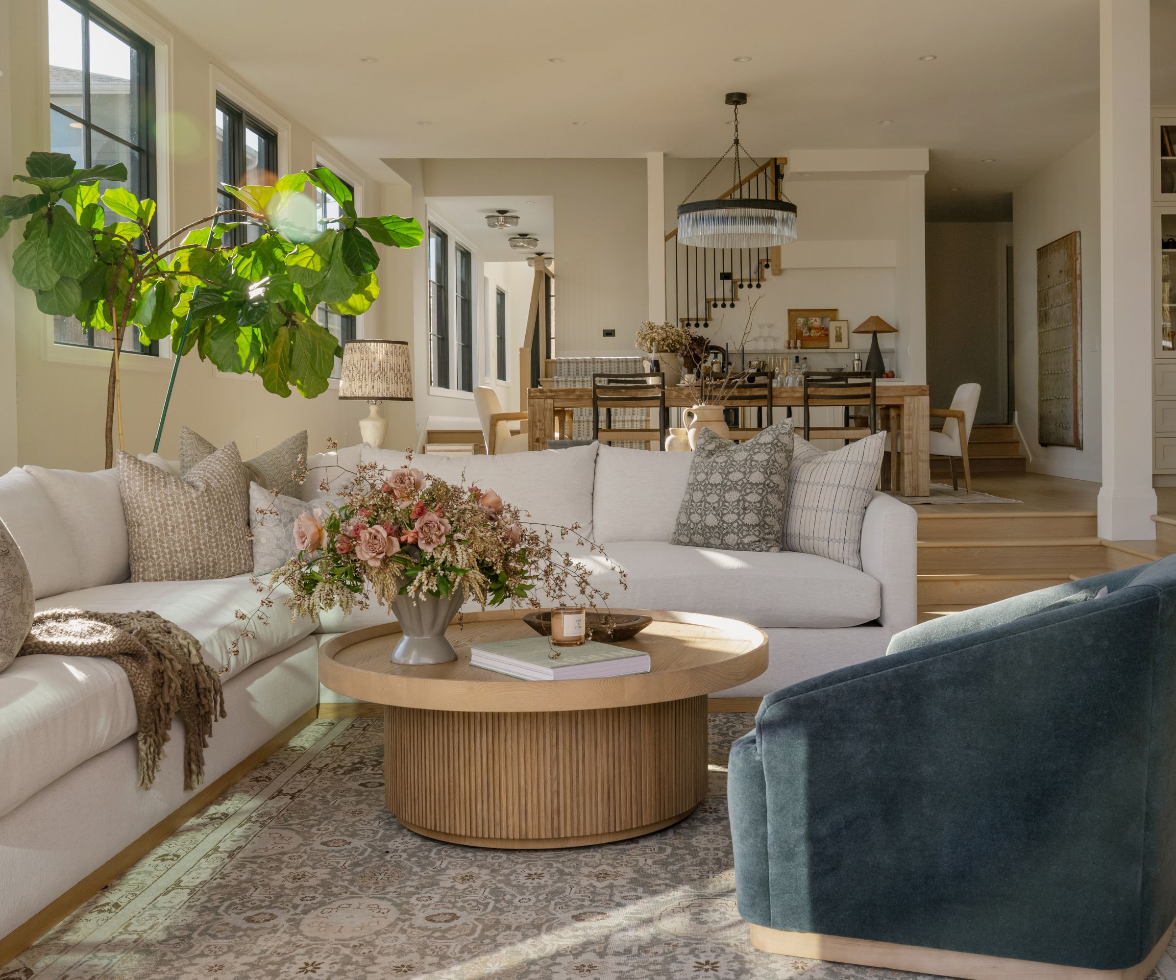 Open plan first floor interior by Cohesively Curated with walls in Swiss Coffee, beige sofa and blue armchair, Cass Photo