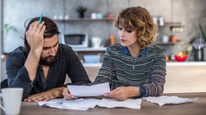 A stressed-looking couple who's getting a divorce go over papers including debt information.