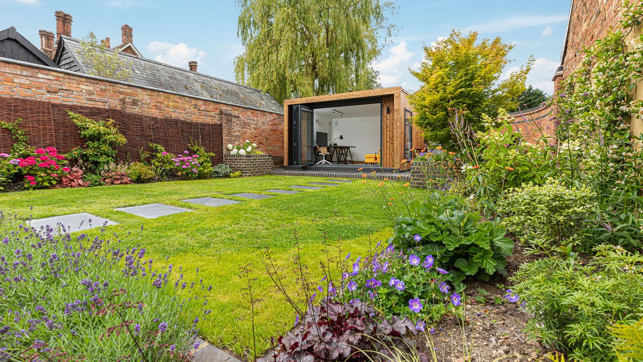 lawn with stepping stone path, borders and garden building