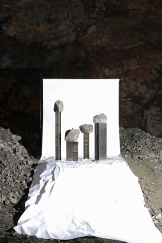 Sculptural pieces by Jinsik Kim featuring a metal bases and large rocks on top, photographed over a white background in a quarry