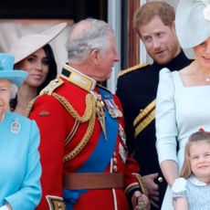 Prince Harry talks animatedly to King Charles with Meghan Markle in the background