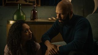 A woman and man sit talking in a dim room