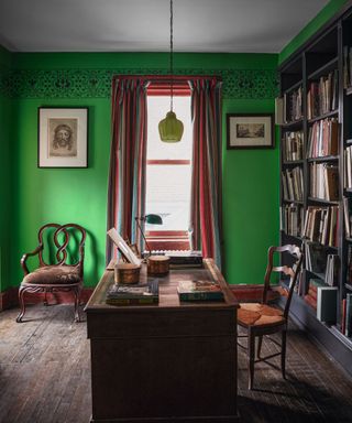 Green walls and lamp, wooden desk, wooden chairs