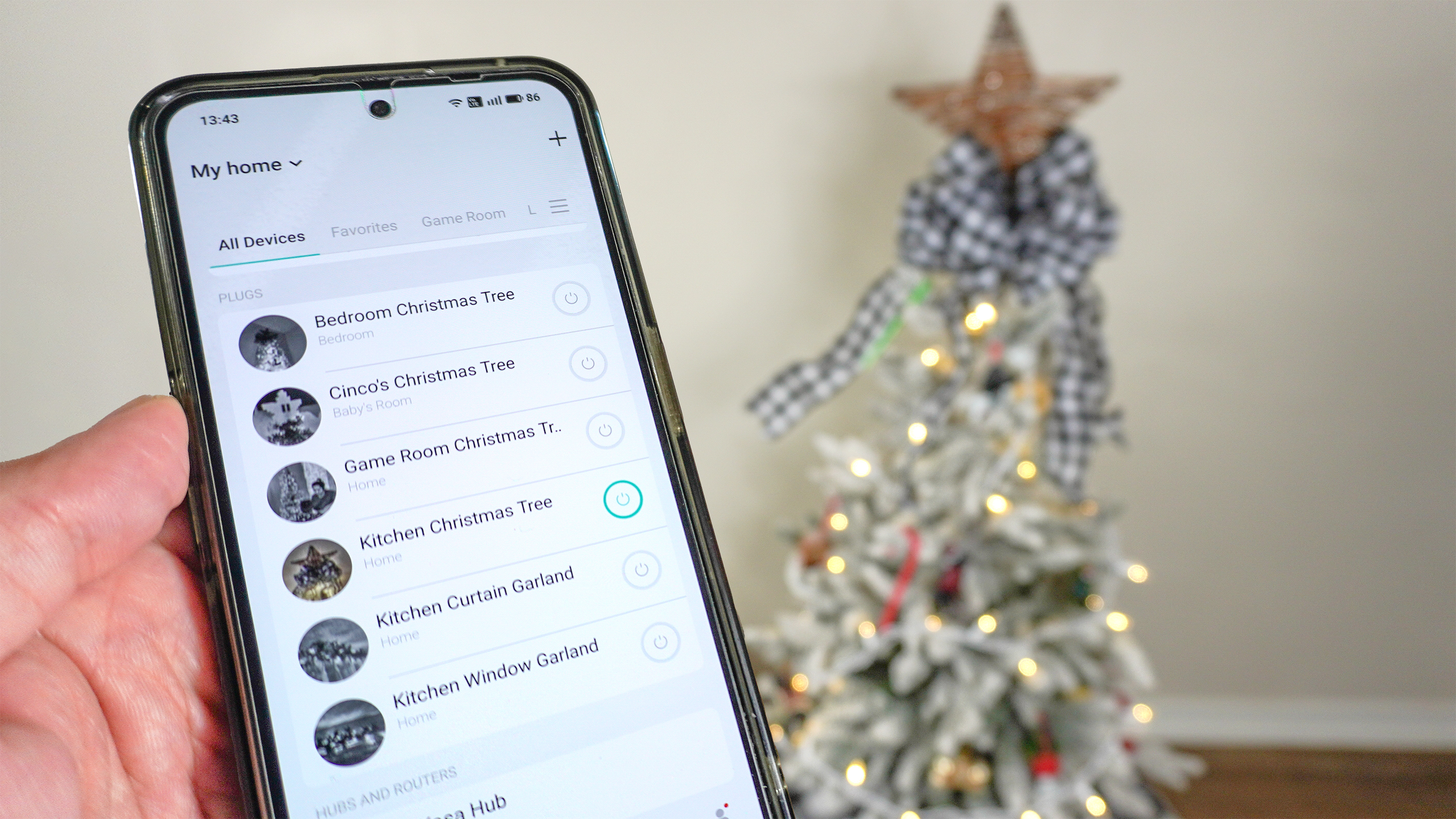 A picture of a person controlling a Christmas tree connected to a smart plug via an app on their phone