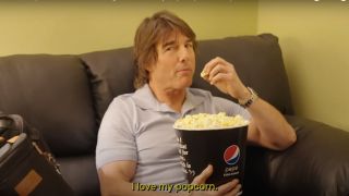 Tom Cruise eats popcorn on a couch in a Mission: Impossible - Dead Reckoning Part One promo.
