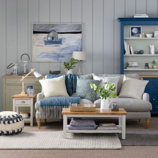 Blue and grey living room with grey sofa, grey carpet and layered rugs