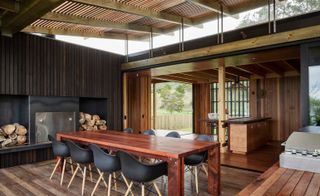Dining area at the retreat. The interior has wooden finishes. Cedar covered fireplace is to the left, while the dining table with black chairs is in the center.