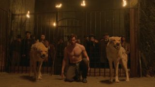 Calahan Skogman as Matthias about to fight in the Hell Show ring, kneeling with a wolf on both sides of him