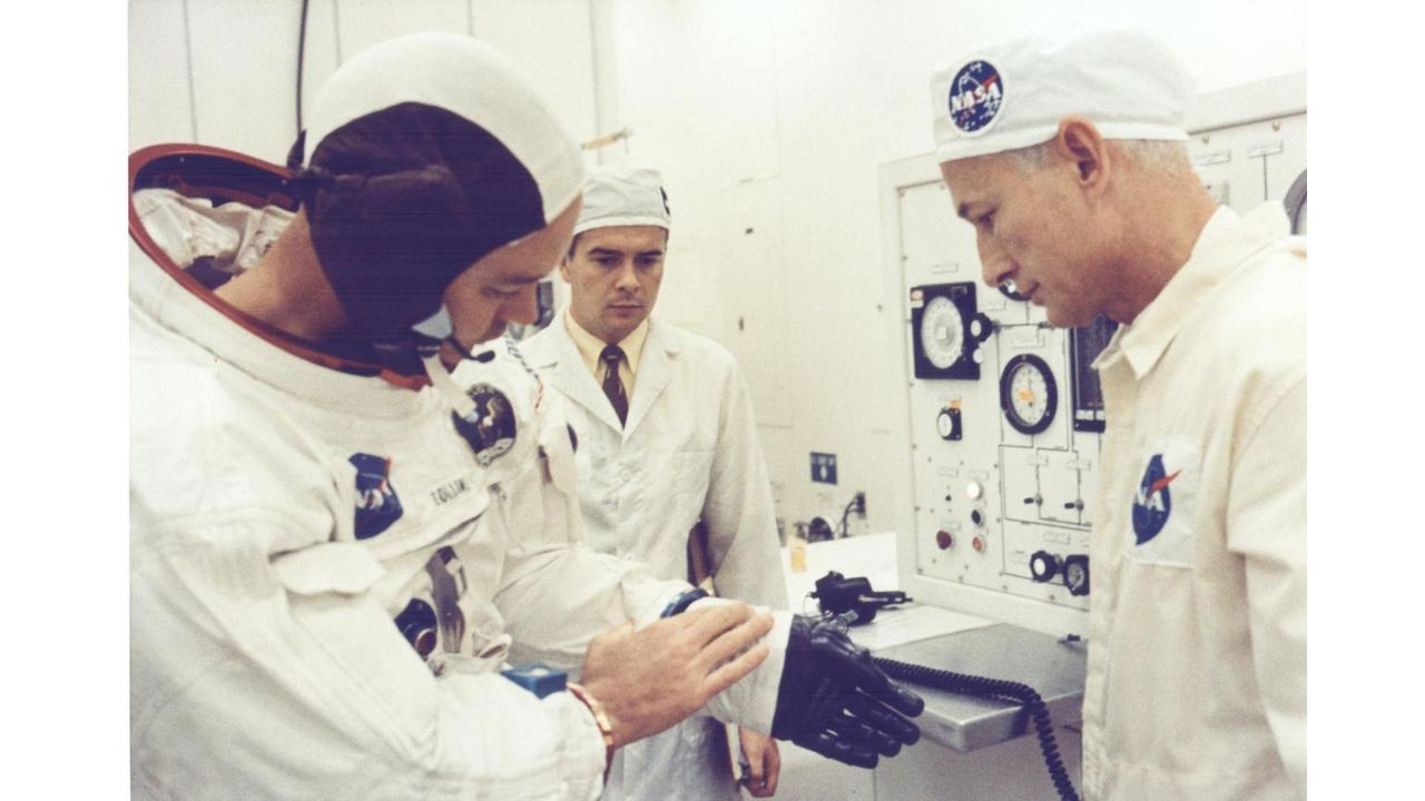 Astronaut Michael Collins seems to be talking about his spacesuit glove with NASA technician Joe Schmitt before the Apollo 11 launch.