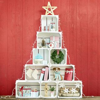 A Christmas tree made from white storage crates with red shiplap wall decor