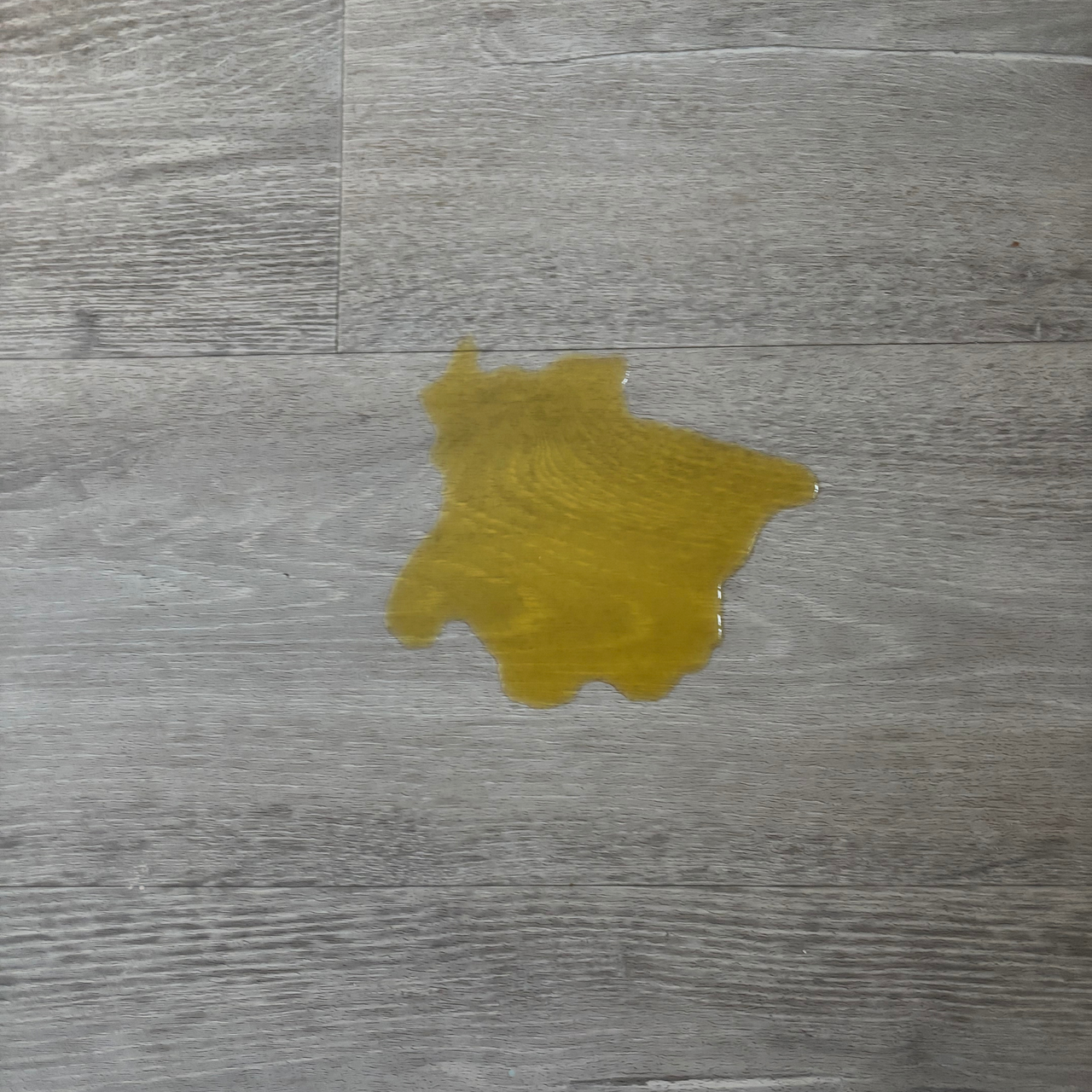 puddle of orange squash on grey laminate floor