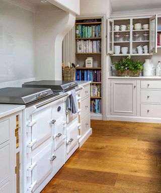 white kitchen with wooden flooring and book shelf