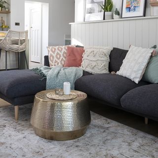 Living room with grey l-shaped sofa, rug and gold coffee table.