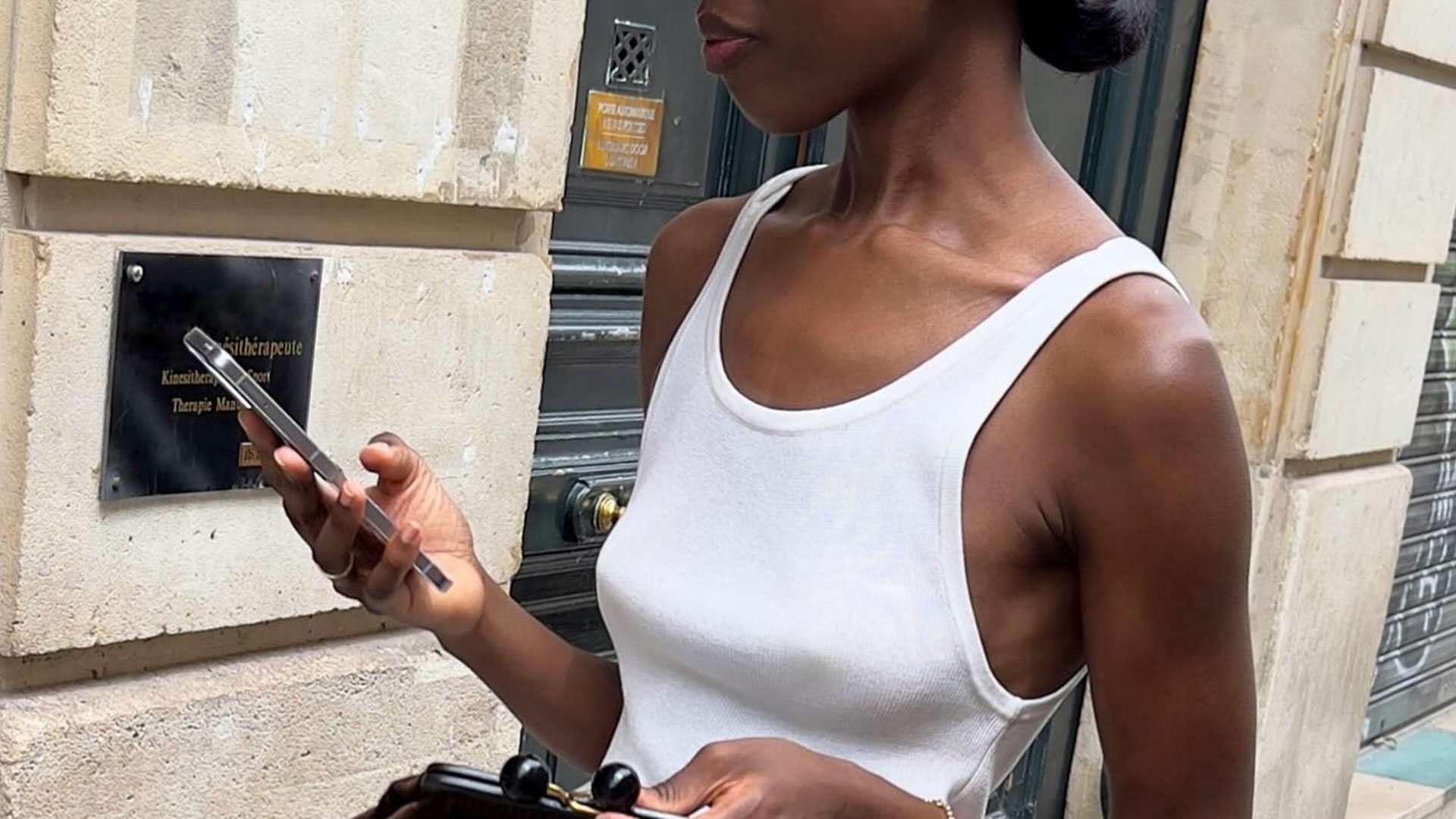 @sylviemus_ outfit shot in white tank with black skirt holding phone.