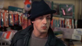 Sylvester Stallone's Rocky inside pet store wearing his black hat and black leather jacket