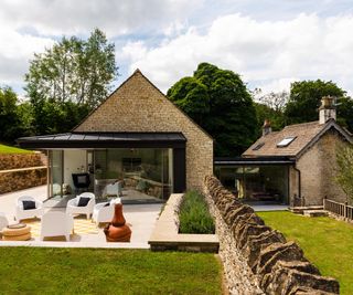 stone-clad pitched roof extension to a traditional cottage with an outside patio with sliding doors