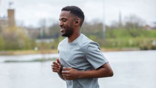 Athletic black male jogging with Shokz Openfit headphones