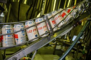 A spiral chrome conveyor lined with cans printed with the time 1:52.