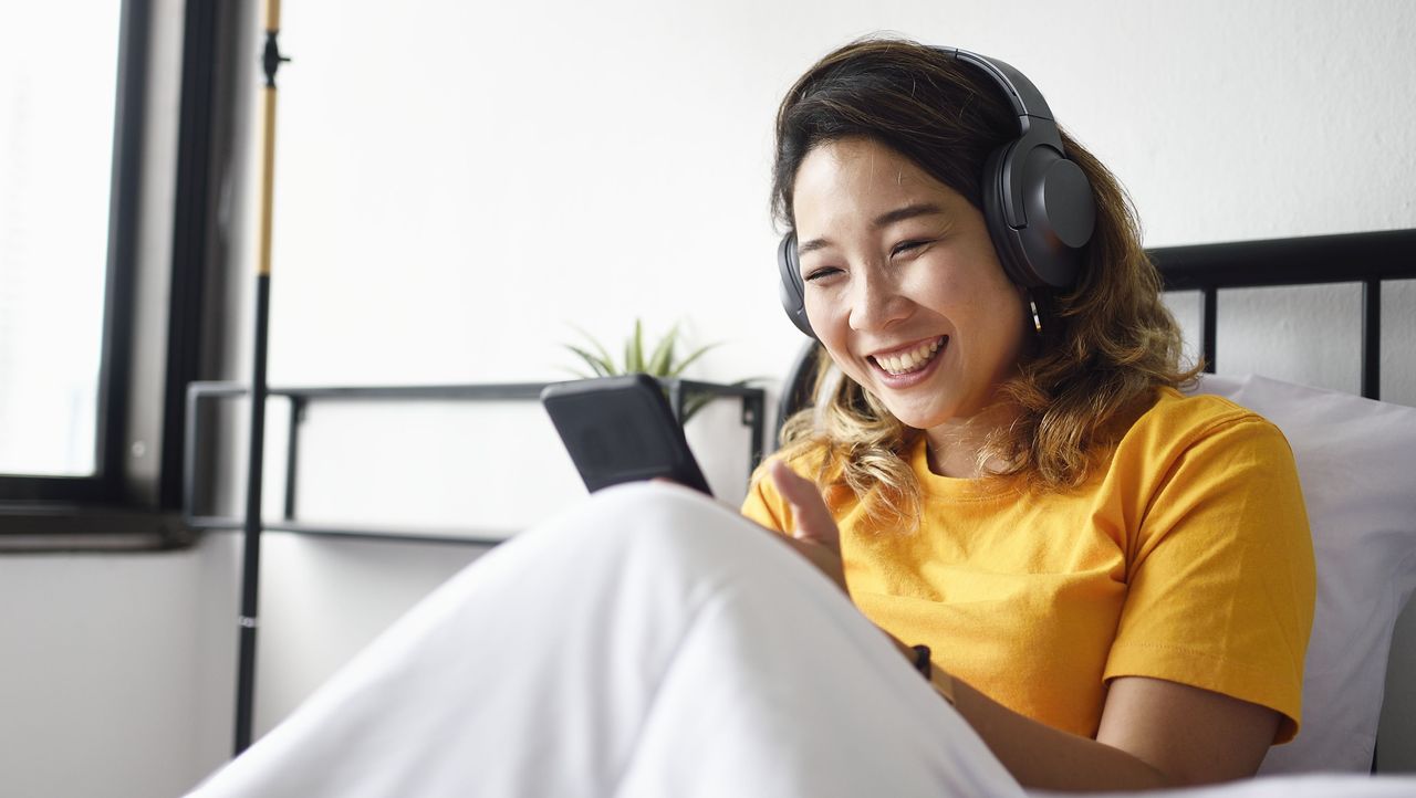 Woman reading from her smart phone in bed, smiling