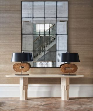 Hallway with parquet floor, console table and large mirror reflecting the staircase. A seven storey townhouse in Kensington, London,