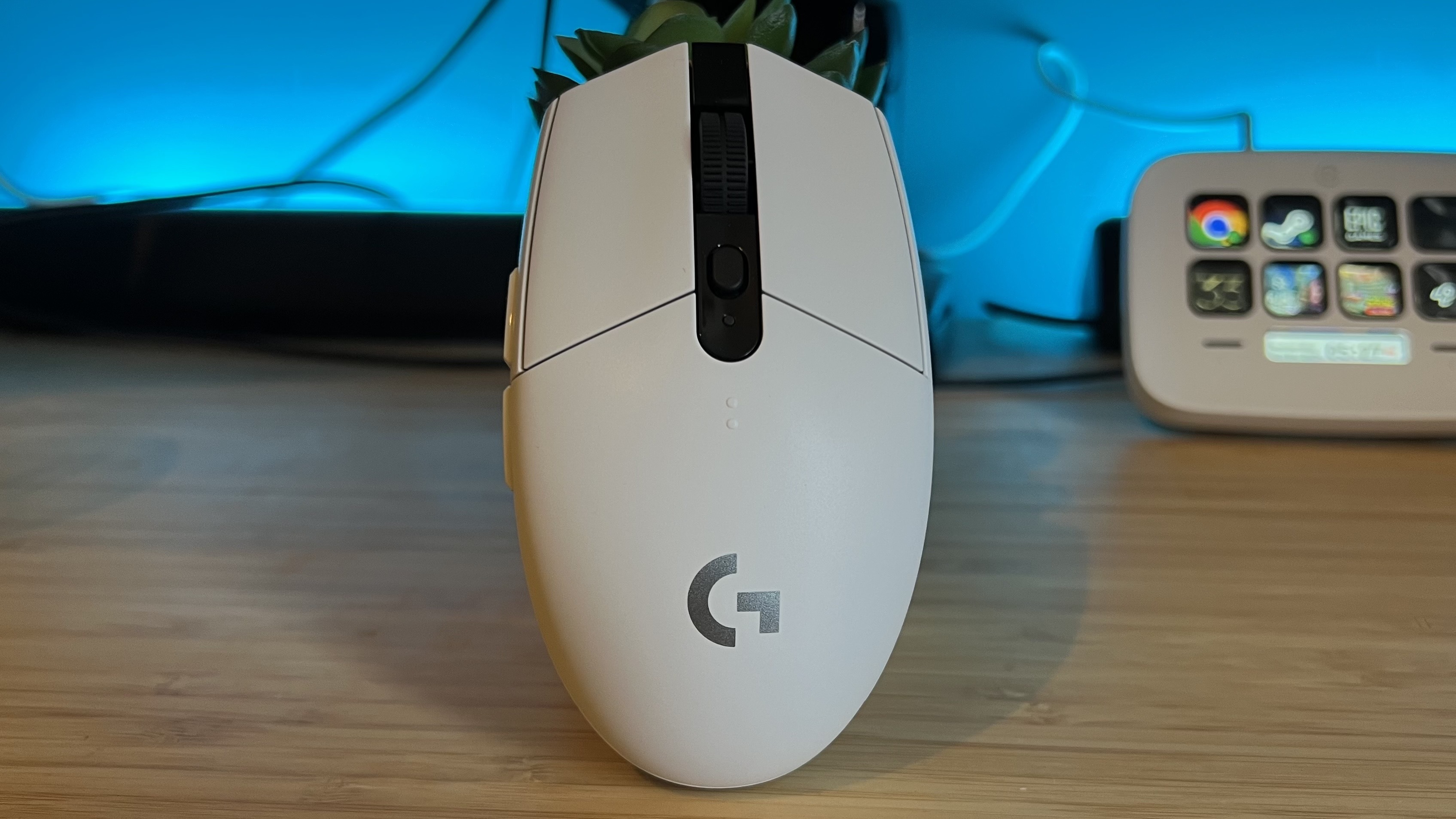 Logitech G305 Lightspeed gaming mouse standing upright on a wooden desk with blue backlighting