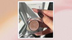 Image of hand with brown almond nails holding Urban Decay's Moondust Eyeshadow in shade 'Space Cowboy' on a pink watercolour background