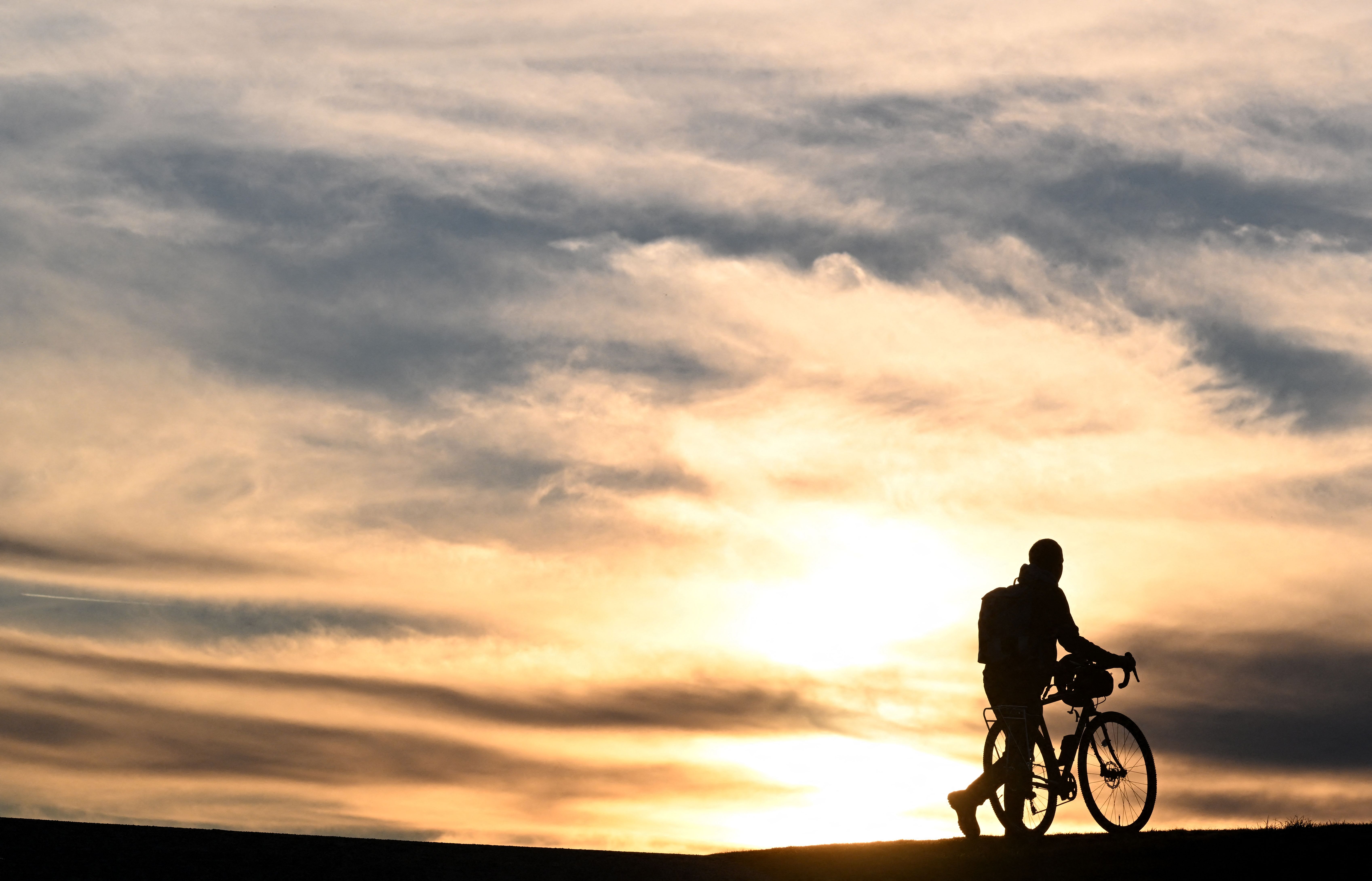 Cyclist walks bike in sunset scene