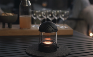 Portable speaker and light glowing, with wine glasses in background