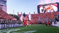The Virginia Tech Hokies run on the field holding an American flag for college football season. 