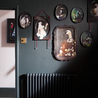 Hallway painted in black with black radiator and gallery wall