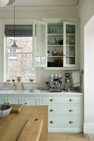 Pastel mint shaker kitchen with marble worktops and a wooden island