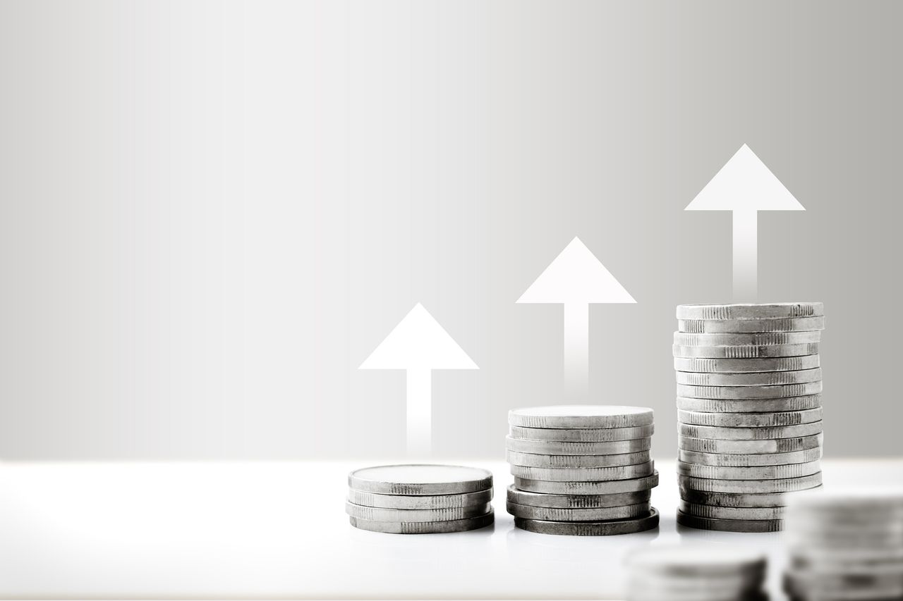 Stack of silver coins with an increase arrow on the table. Financial investment concept