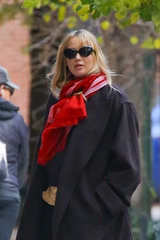 jennifer lawrence wearing red scarf, black coat, navy sweater, yellow button-down shirt