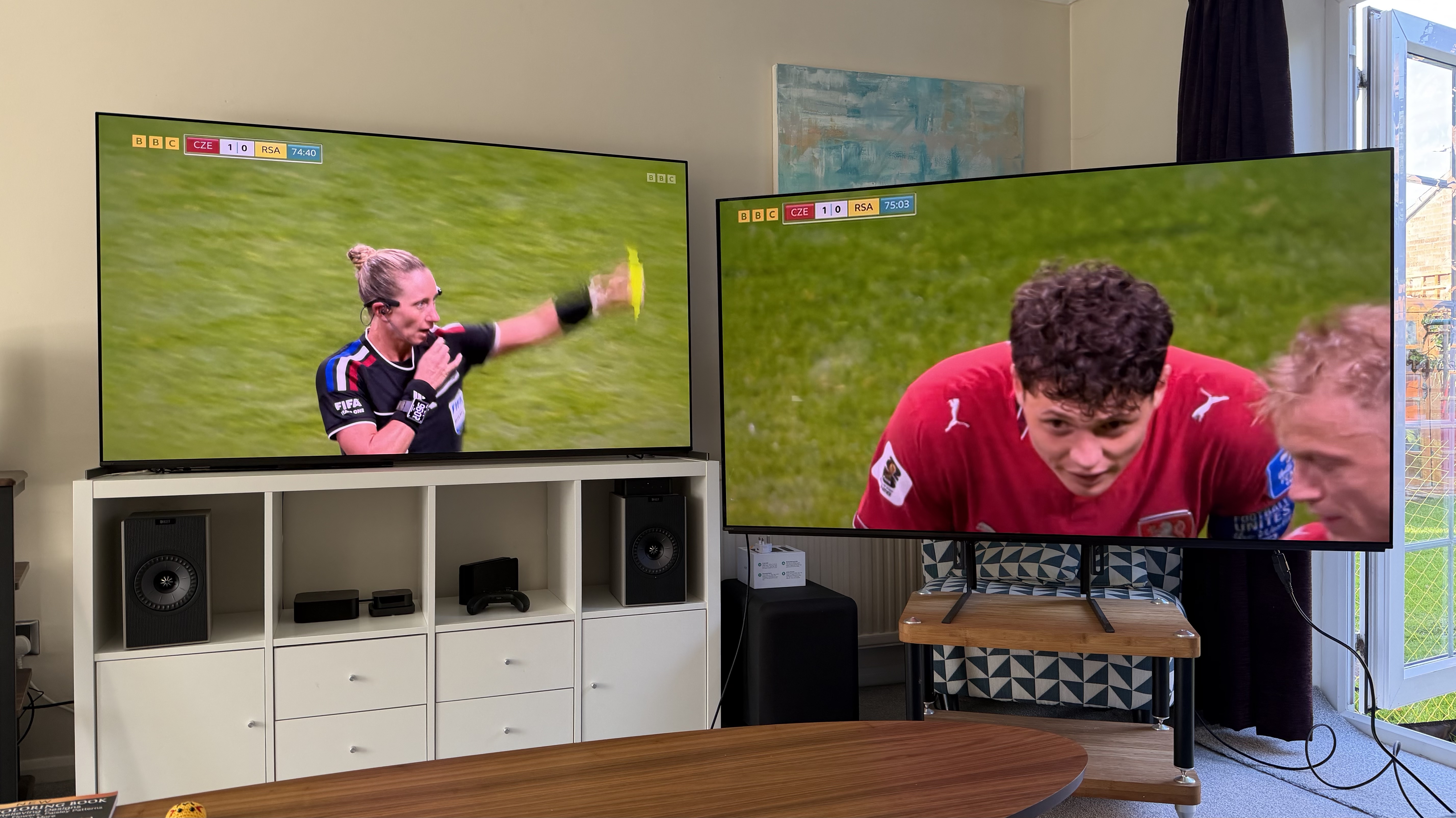 Two 65-inch TVs showing football, pictured in a living room