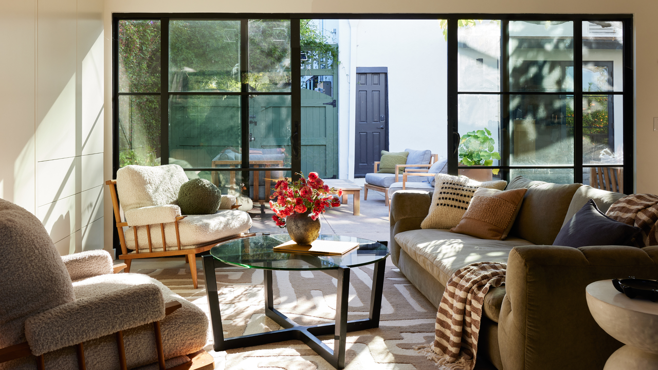 Cozy living room with boucle armchair, couch and round glass-top coffee table overlooking patio