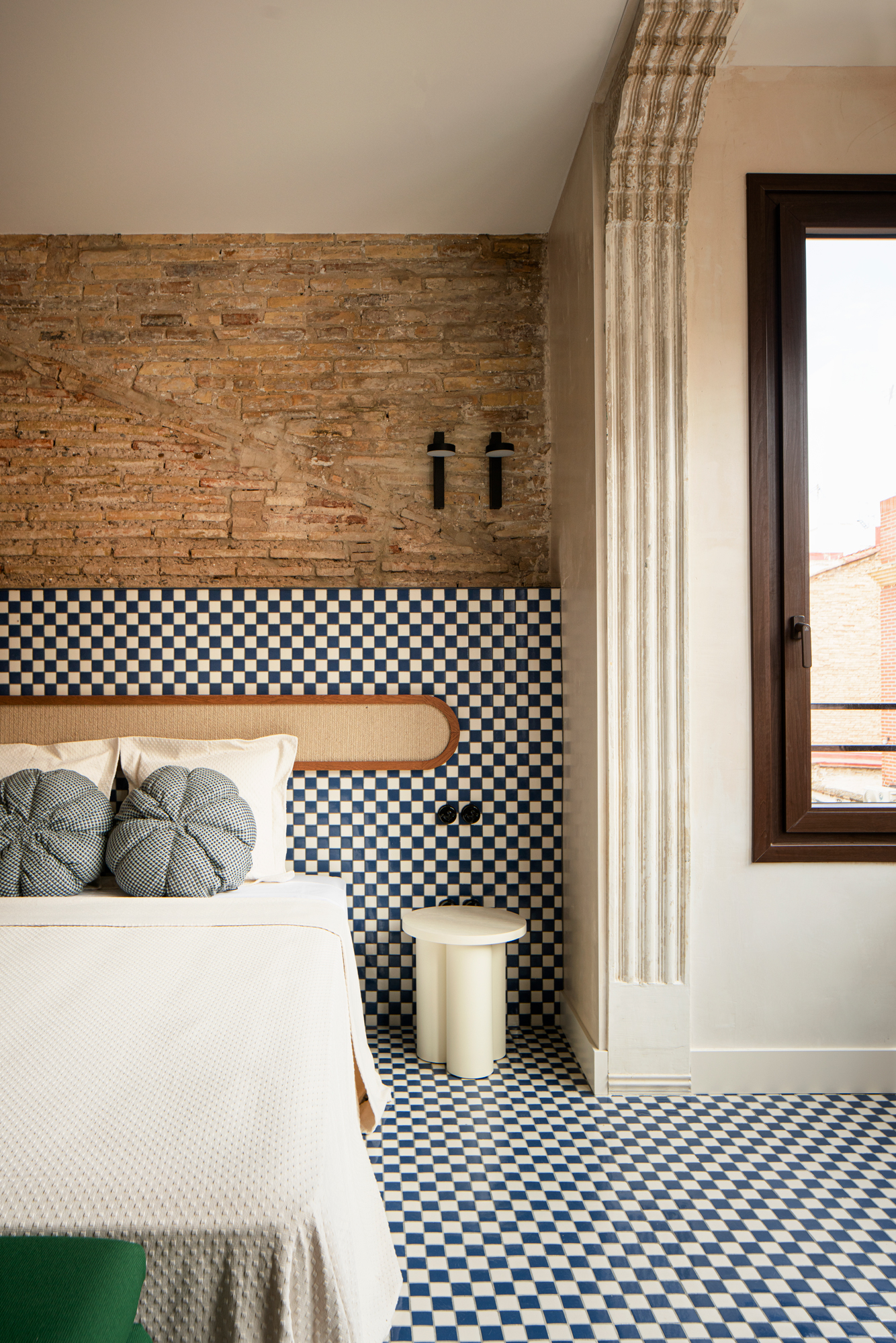 A contemporary bedroom with walls in checkerboard tiles and exposed brick