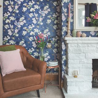 white painted brick fireplace in room with pretty blue wallpaper with flowers