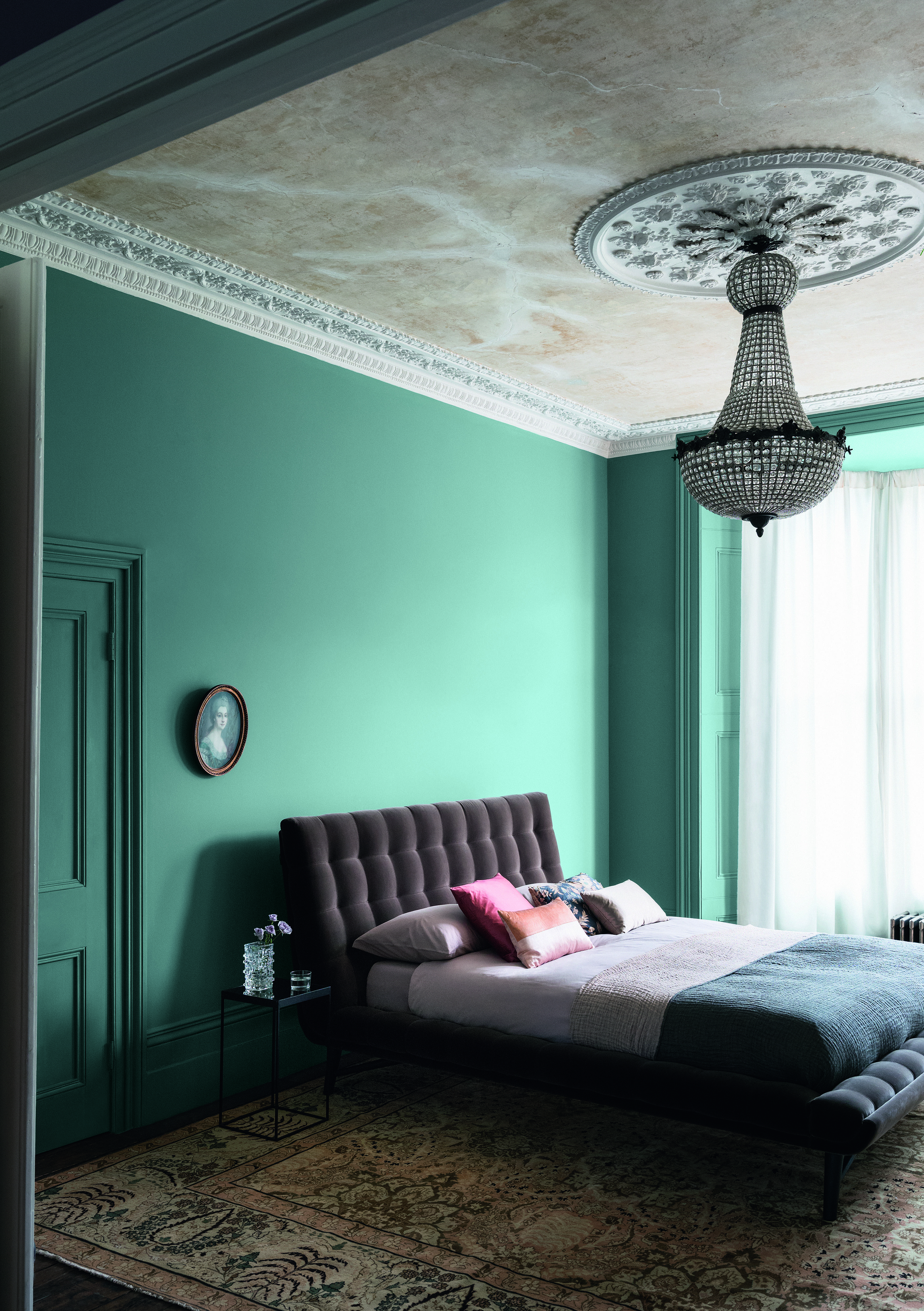 Green bedroom with color drenching on doors and walls, vintage rug and chandelier, by Paint & Paper Liibrary