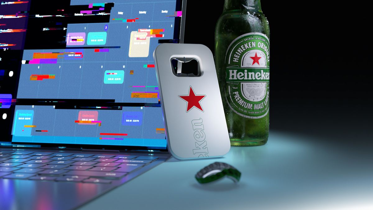 Heineken&#039;s &#039;The Closer&#039; bottle opener leaning against a bottle of Heineken lager, in front of open laptop showing coloured spreadsheet