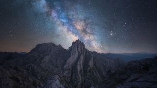 The Milky Way core streaking over a rock formation against a background of stars.