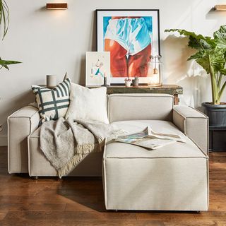 living area with sofa and wooden floor and white wall and painting frame