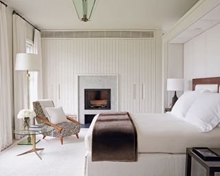 Panelled white bedroom with white panels and fireplace