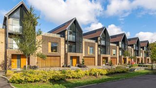 A row of contemporary terraced houses with wooden garage doors and gable end roofs