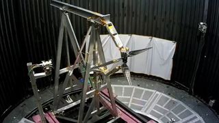 a set of industrial beams provide a frame to hold dual rotor blades for a spin test in a black enclosed chamber.